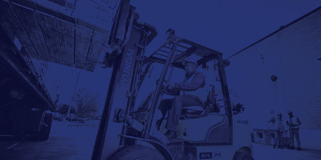 a guy in a forklift, loading a large wooden pallet